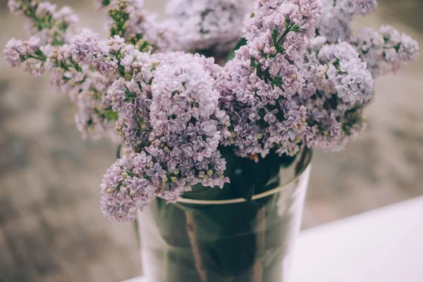 Closeup shot of beautiful lilacs in a metal vase on blurred background