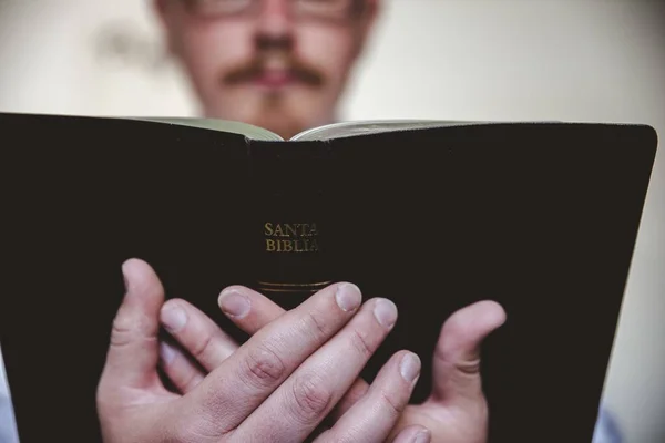 Close-up tiro de um macho lendo a bíblia com um fundo borrado — Fotografia de Stock