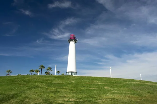 Vue en angle bas d'un phare isolé dans un champ vert sous le beau ciel nuageux — Photo