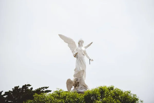 Hermosa foto de una estatua femenina blanca con alas y un cielo nublado en el fondo — Foto de Stock