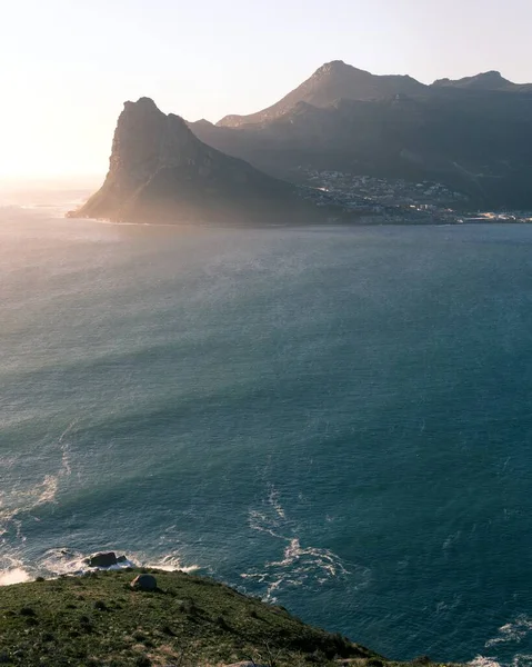 Güneşli bir günde suyun yanında bir tepenin dikey görüntüsü — Stok fotoğraf