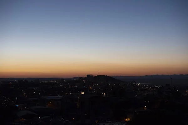 Hermosa toma de edificios de la ciudad con bajo un cielo naranja y azul oscuro una puesta de sol —  Fotos de Stock