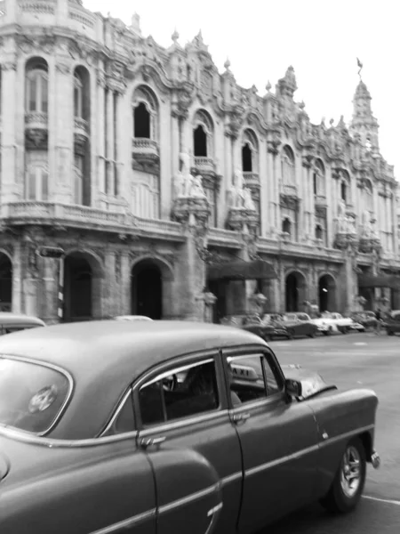 Vertikal gråskala skott av en retro bil kör på gatan bredvid den stora teatern i Havanna — Stockfoto