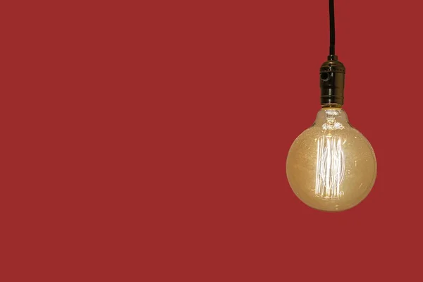 Old vintage yellow  electric lightbulb on a red background — Stock Photo, Image