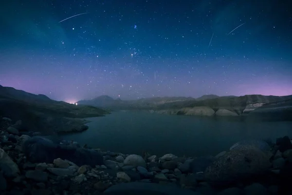 Hoge hoek opname van een prachtig meer omgeven door rotsen onder de adembenemende sterrenhemel — Stockfoto