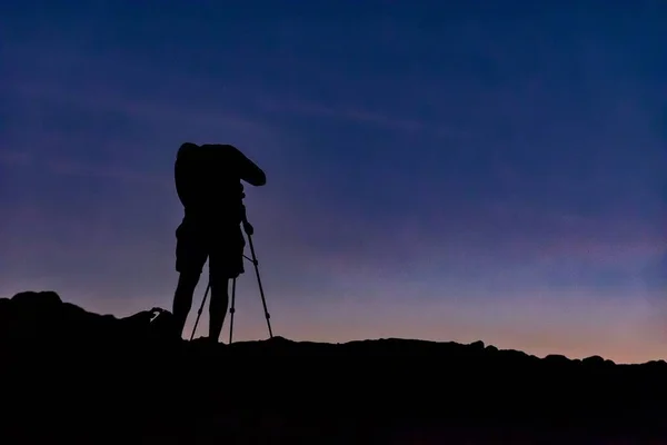 Silhouette of a photographer on a hill under the beautiful sky