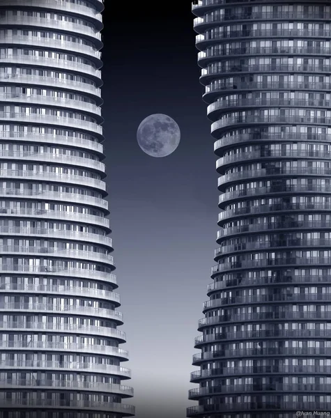 Incroyable plan de deux sombres bâtiments futuristes courbes avec la pleine lune au milieu de la nuit — Photo