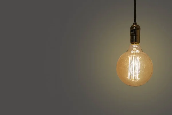 Starý vintage žlutá elektrická žárovka na béžové pozadí — Stock fotografie
