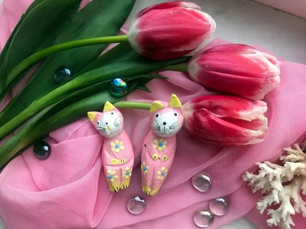 三个新鲜的粉色郁金香和两只躺在粉色布上的小玩具猫的高角镜头 — 图库照片