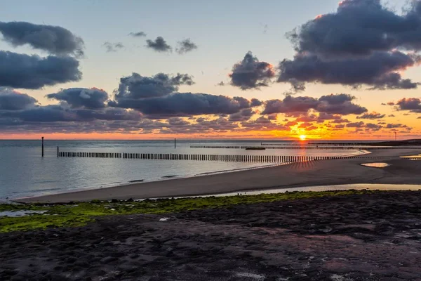 Paisagem de tirar o fôlego de um pôr do sol sobre o cais do oceano em Westkapelle, Zelândia, Países Baixos — Fotografia de Stock