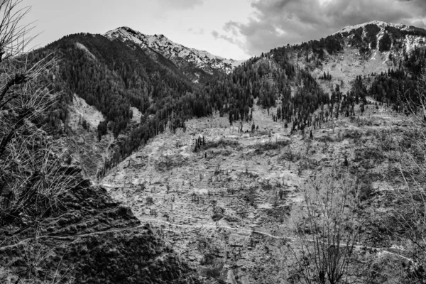 Grayscale shot of high rocky mountains under the cloudy sky — Stock Photo, Image