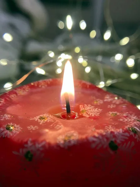 Vertikale Nahaufnahme einer großen roten brennenden Weihnachtskerze mit darauf abgebildeten weißen Schneeflocken — Stockfoto