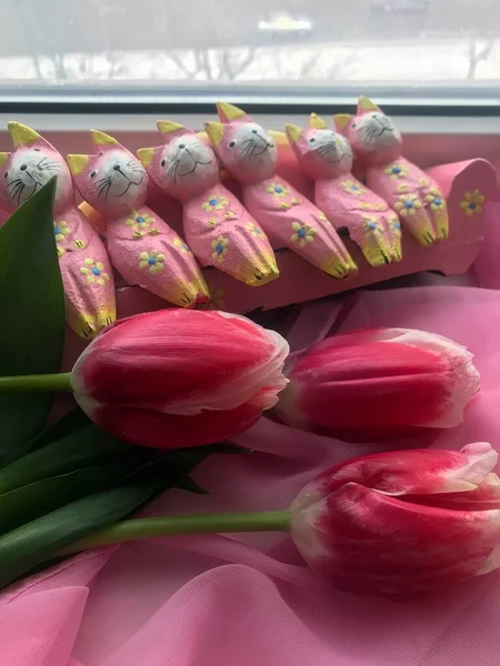 Tiro vertical de alto ângulo de três tulipas rosa frescas e muitos pequenos gatos de brinquedo deitados em um pano rosa — Fotografia de Stock