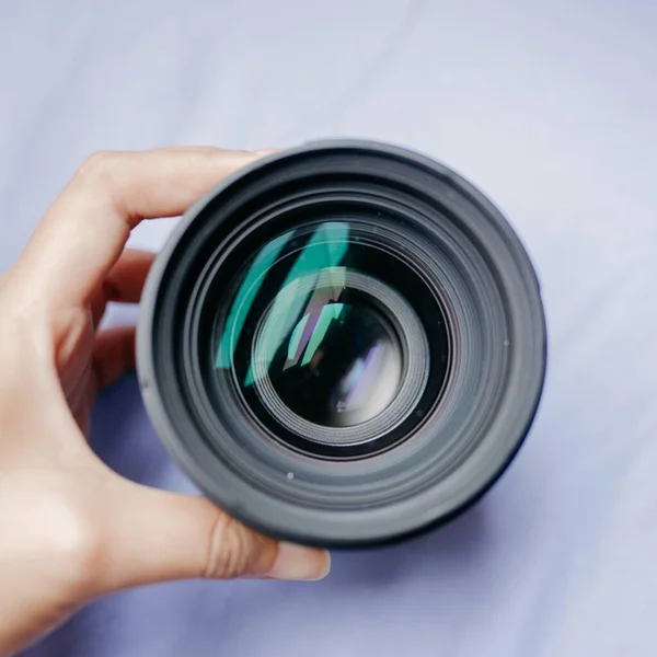 Tiro de ângulo alto de uma pessoa segurando uma lente da câmera em um fundo branco — Fotografia de Stock