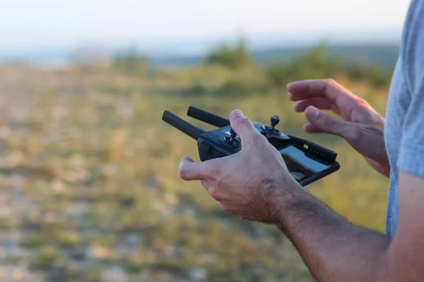 Close-up tiro de uma pessoa que controla um drone com um controle remoto em um fundo turvo — Fotografia de Stock