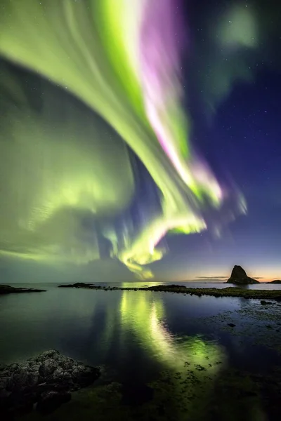 Vertical shot of the reflection of the beautiful northern lights in the sea captured in Norway