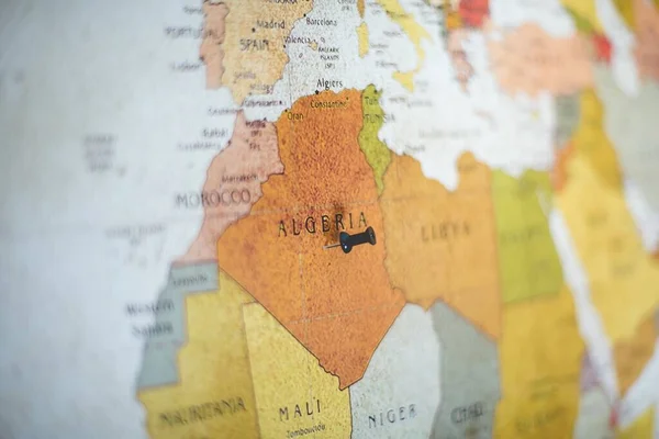 Closeup shot of a black pin on Algeria country on the map with a blurred background — ストック写真