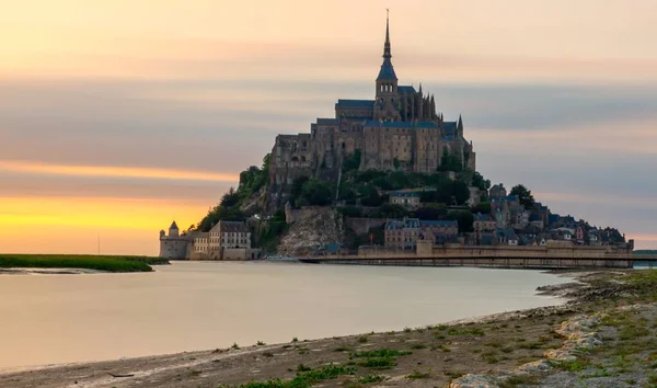 Hermosa foto de la famosa abadía de Mont-Saint-Michel cerca del lago bajo el cielo colorido — Foto de Stock