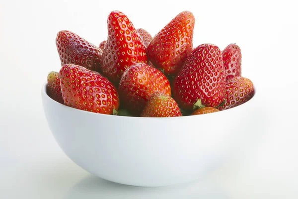 Primer plano de un tazón blanco lleno de fresas frescas y deliciosas sobre un fondo blanco — Foto de Stock