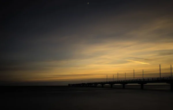 Krásný záběr na dřevěný dok u moře pod západem slunce — Stock fotografie