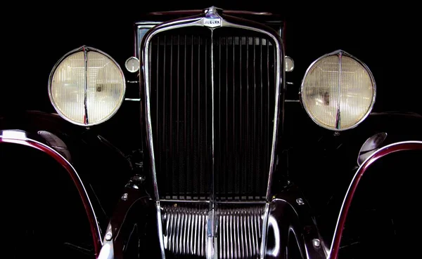 Closeup tiro de uma parte dianteira de um carro vintage vermelho escuro com uma textura brilhante — Fotografia de Stock