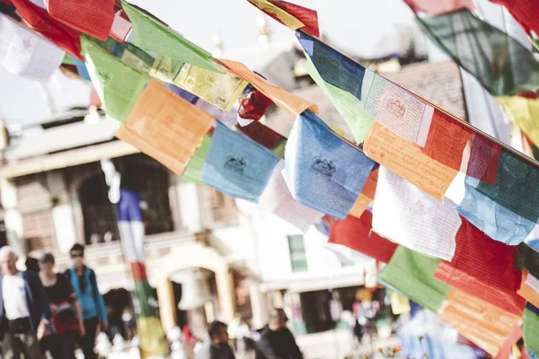 Szoros felvétel egy zsinórról lógó ruhadarabokról, homályos háttérrel a nepáli buddhista templomban. — Stock Fotó