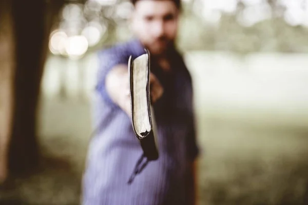 Primer Plano Macho Sosteniendo Biblia Hacia Cámara Con Fondo Borroso —  Fotos de Stock