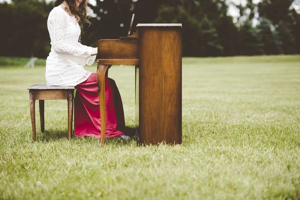 在一个背景模糊的草地上弹钢琴的女性的特写镜头 — 图库照片