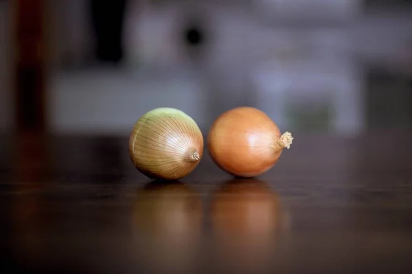 Photo de fermeture de deux oignons sur une surface en bois avec un fond flou — Photo