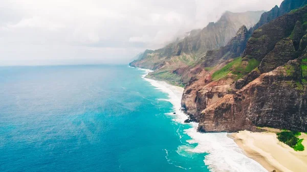 ハワイのカウアイ島で撮影された美しいハマグリの海によって岩の崖の高角度ショット — ストック写真