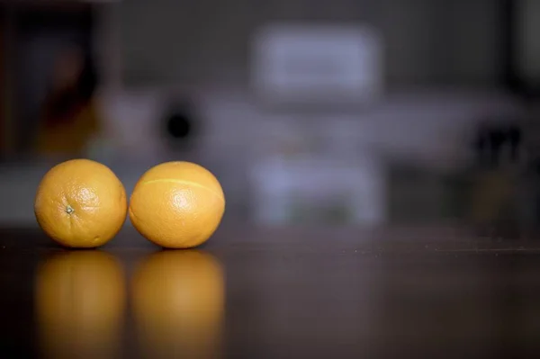 Primer plano de dos naranjas sobre una superficie de madera con un fondo borroso — Foto de Stock