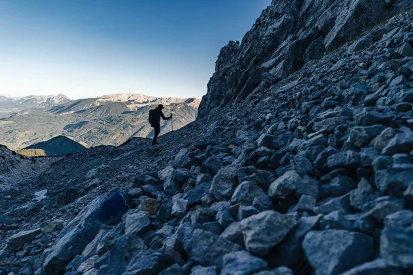 Low angle shot of an adventurous person hiking a mountain full of rocks in Totes Gebirge, Austria