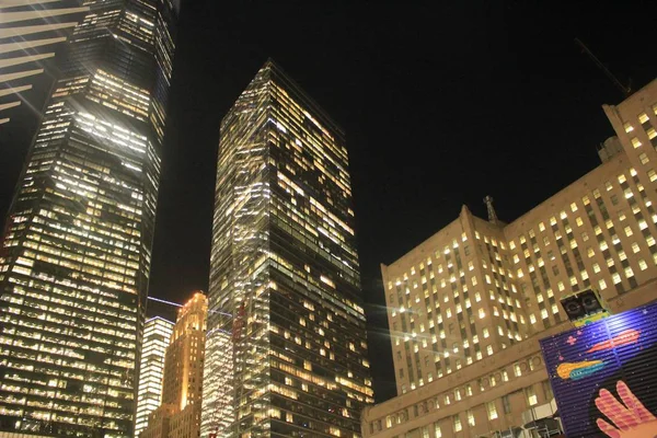 Low angle shot of high-rise buildings spreading light during nighttime — Stock Photo, Image