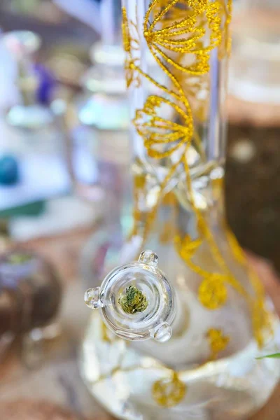 Verticale close-up shot van een cannabis bong met gouden patronen op wazige achtergrond — Stockfoto