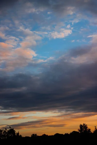 Tiro vertical de um belo pôr do sol com cores únicas no céu nublado — Fotografia de Stock