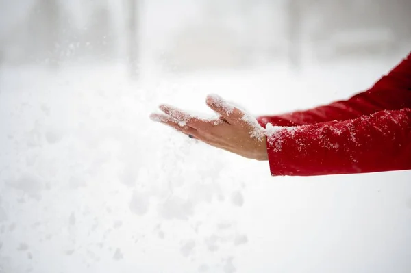 Close-up tiro de um macho segurando neve com as palmas das mãos e um fundo borrado — Fotografia de Stock