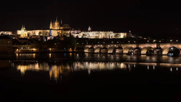 Beautiful shot of the famous Charles Bridge in Prague with the reflection of lights in the river — Stock Photo, Image