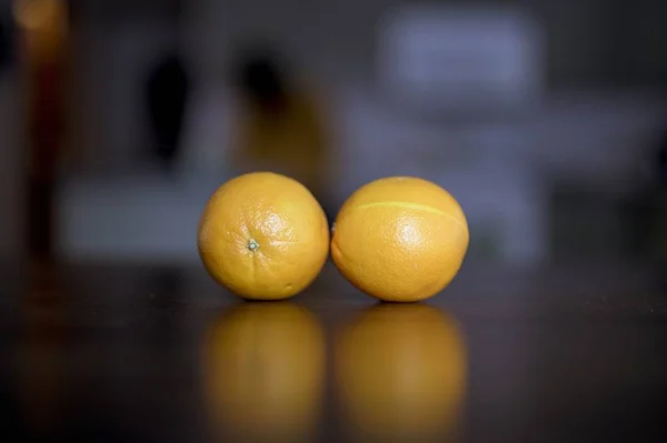 Nahaufnahme von zwei Orangen auf einer Holzoberfläche mit unscharfem Hintergrund — Stockfoto