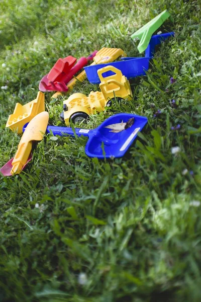 Tiro vertical de brinquedos plásticos coloridos em um campo coberto de grama — Fotografia de Stock