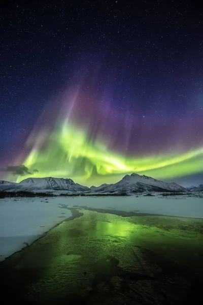 Scatto verticale del riflesso delle colorate luci del nord nel mezzo lago ghiacciato — Foto Stock