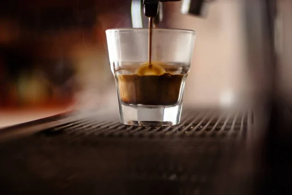 A closeup shot of an Irish coffee being poured in a glass from a coffee machine