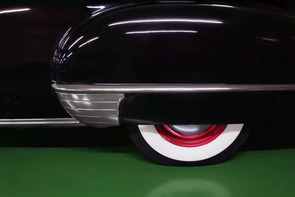 stock image A closeup shot of a glossy black car with red and white wheels on a green surface