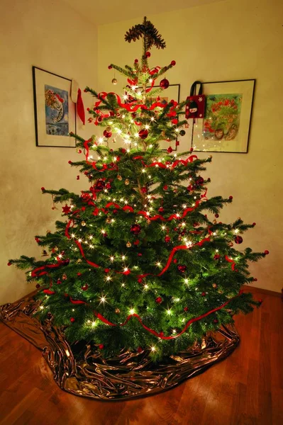 Magnifiquement décoré arbre de Noël avec des ornements et des lumières à cordes à l'intérieur d'une pièce — Photo