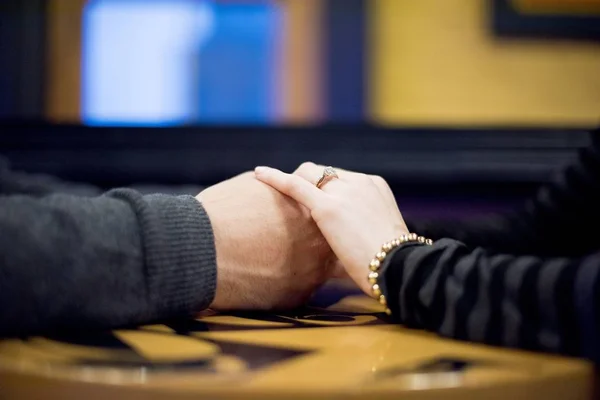 Close-up tiro de um casal de mãos dadas sobre a mesa com um fundo borrado — Fotografia de Stock