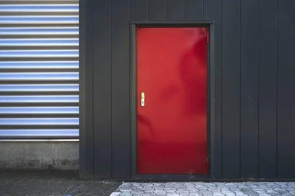 Edificio con pareti nere e argentate e una porta rossa sul pavimento — Foto Stock