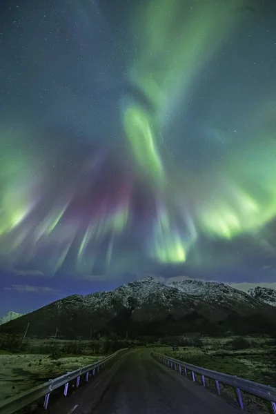 Verticale opname van een weg onder het prachtige noorderlicht in de lucht — Stockfoto