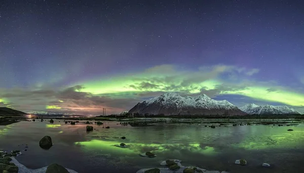 The beautiful reflection of the northern lights in a lake surrounded by snow covered mountains