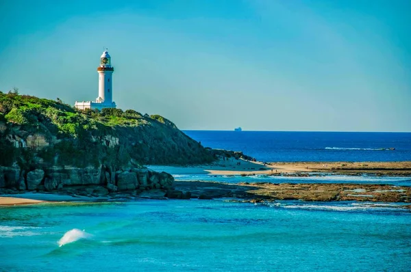 Schöne Aufnahme eines Leuchtturms auf einer Felsformation am Meer unter klarem Himmel — Stockfoto