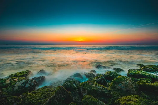 Moss covered stone by a beautiful ocean under the sunset captured in Westkapelle, Netherlands — Stock Photo, Image