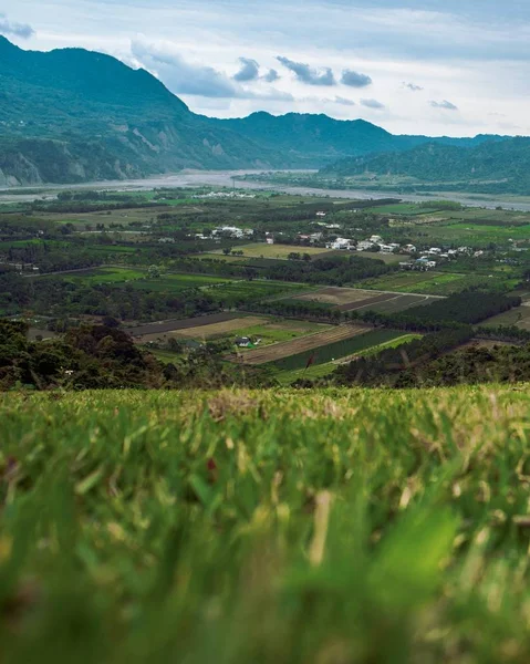 Luchtfoto van een prachtig groen landschap omgeven door een groene bergketen onder bewolkte lucht — Stockfoto